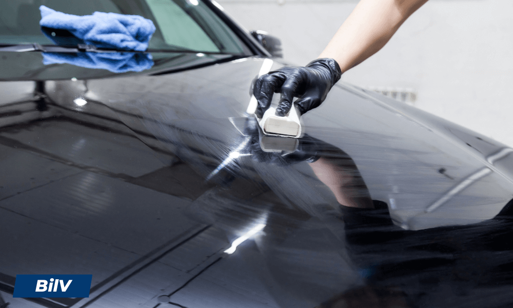 Applicering av karnaubavax på svart motorhuv med skumapplikator för spegelblank finish