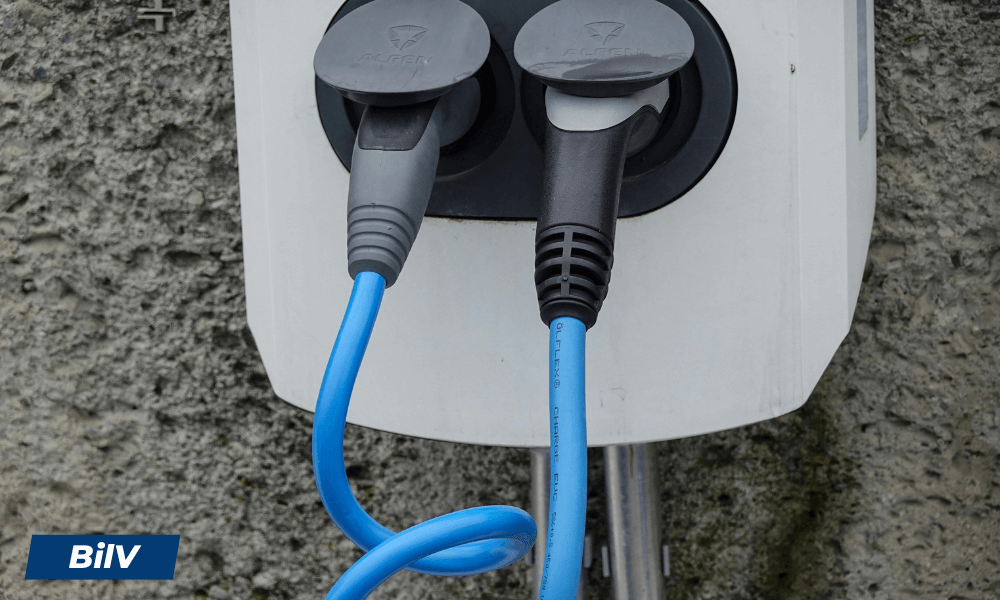 Blå elbilsladdare inkopplad i laddbox, visar anslutning med två kablar till elbilens laddstation.
