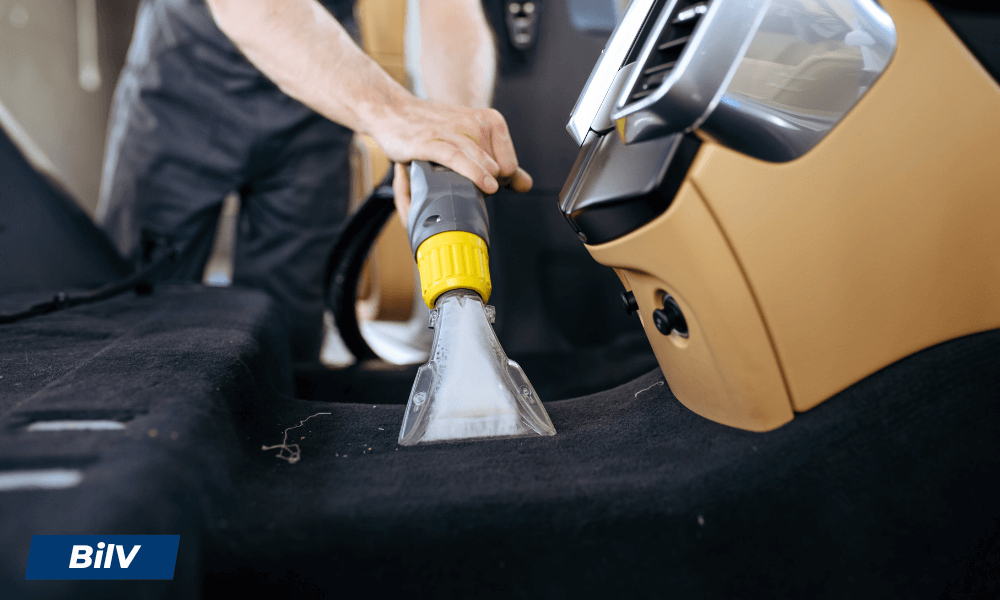 Bilmatta rengörs med textilmunstycke kopplat till grovdammsugare, idealisk för bilinredning.