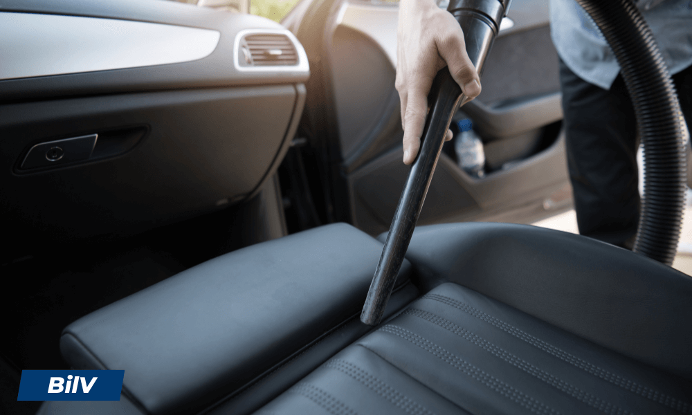 Bilklädsel dammsugs med smalt munstycke, visar användning av grovdammsugare i bilinteriör.